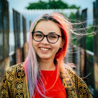 Smiling woman with glasses and multi-coloured hair