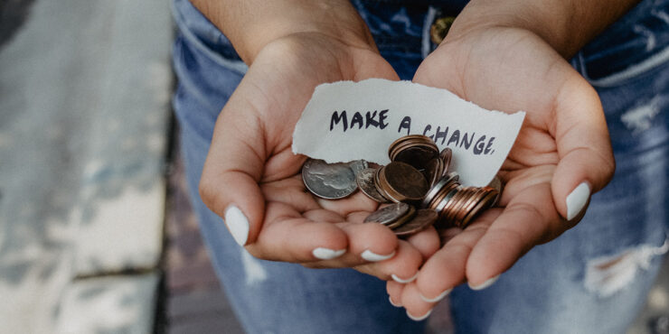 Two hands holding a pile of change with a note that says Make a Change