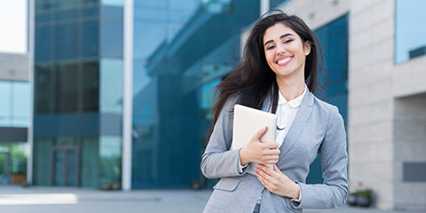 Young female student of business school with tablet on the urban background