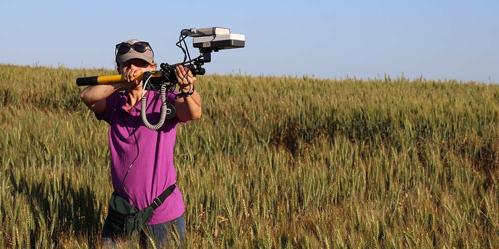 Female in a field holding tech